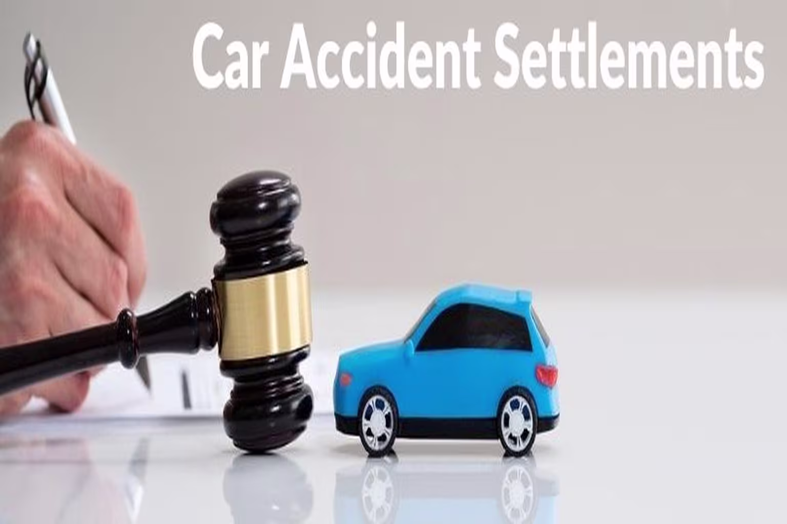 Gavel and toy car on a table, symbolizing car accident settlements and legal action.