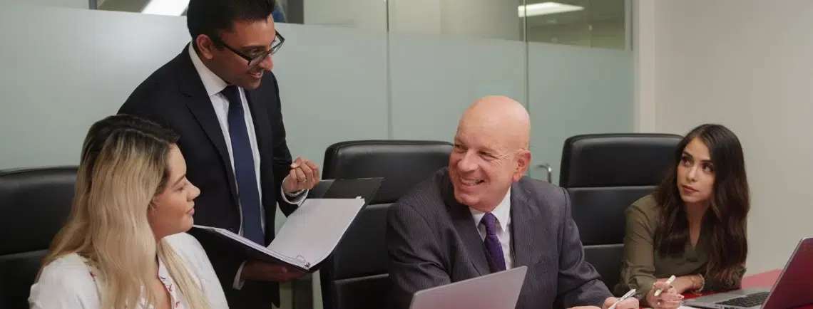 Four professionals engaged in discussion around a meeting table.