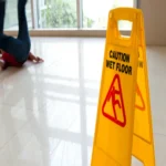 Caution wet floor sign with person who slipped on wet reflective floor